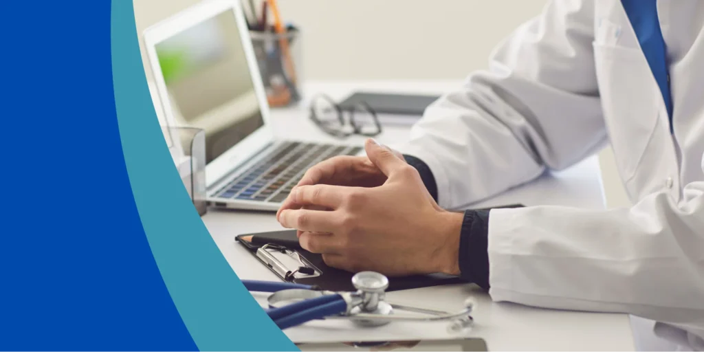 Medical professional consulting at a desk with a laptop and a stethoscope, illustrating the process of how to claim for medical negligence and gather medical evidence