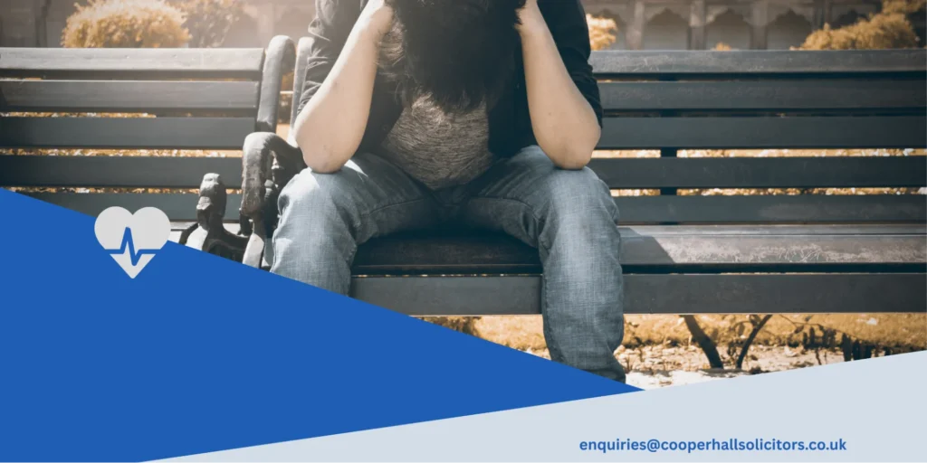 A distressed person sitting alone on a park bench with their head in their hands, representing emotional distress caused by NHS negligence, Cooper Hall Solicitors, Bradford clinical negligence lawyers. 