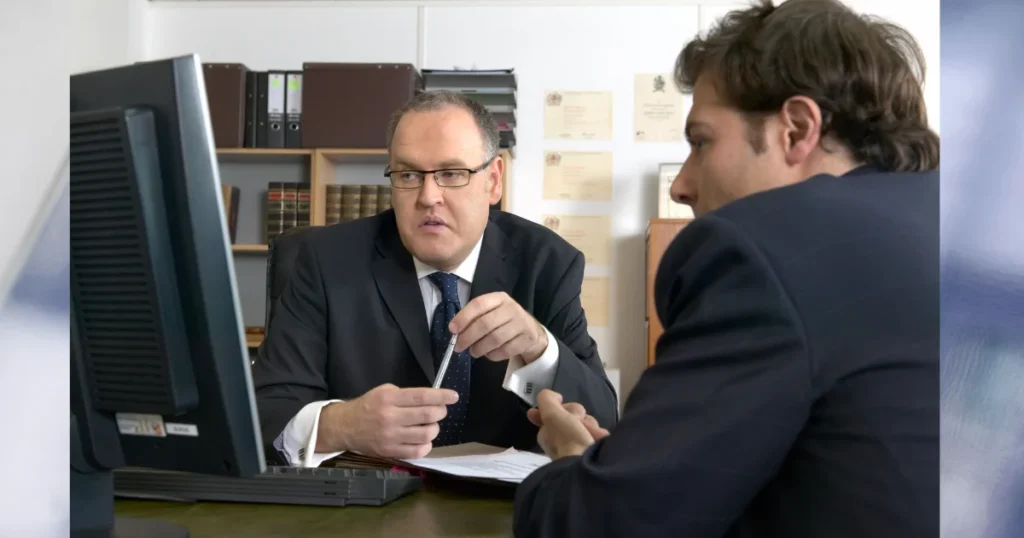 Solicitor discussing a compensation case with a client in an office, providing guidance on how to check CICA claim progress, understand claim updates, and navigate the criminal injury compensation process.